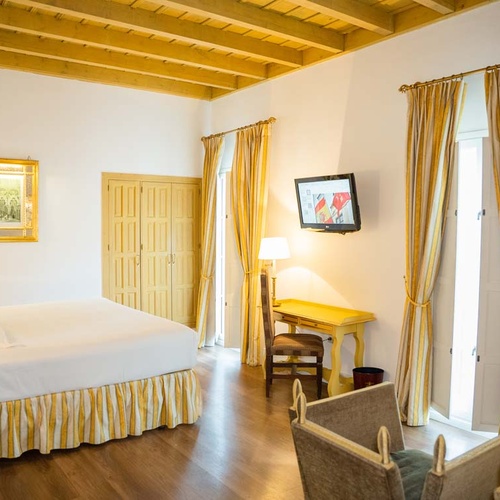 Elegant hotel room in Juderia: Cordoba featuring a large bed, desk, and TV.