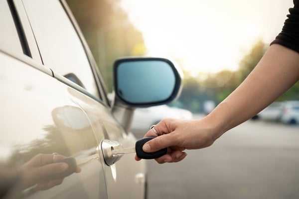 una persona sostiene una llave para abrir la puerta de un coche