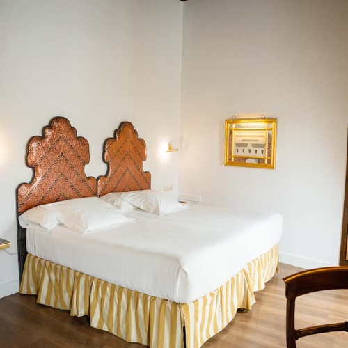 Elegant bedroom at Juderia: Cordoba hotel with ornate headboard and plush bedding.