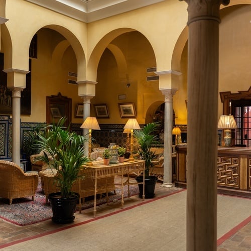 Hotel courtyard in Sevilla's Juderia: archways, seating, and decor.