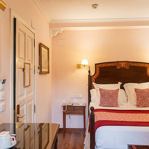 Chambre d'hôtel confortable avec un lit queen-size, un telephone, et un grand tableau. Idéal pour votre Juderia: Sevilla.