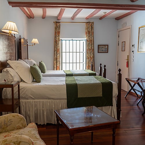 Chambre avec deux lits jumeaux, lampe murale, et vue sur fenêtre, idéale pour un séjour à Juderia: Sevilla.