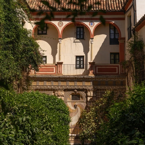 Historic Juderia: Sevilla courtyard hotel with lush greenery and ornate architecture.