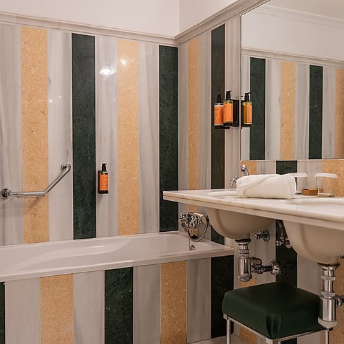 Salle de bain élégante avec baignoire, double lavabo et mosaïque de marbre rayée, idéale pour votre Juderia: Sevilla.