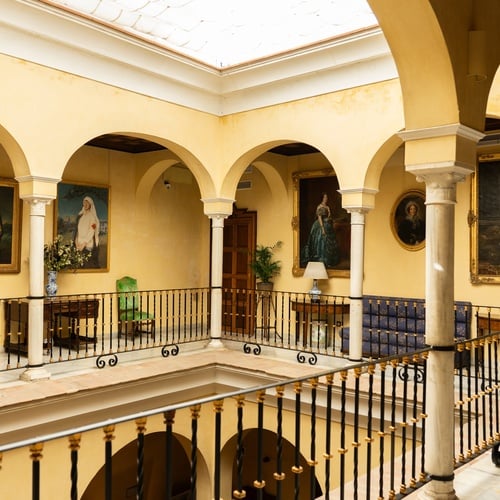 Elegant courtyard with arches, paintings, and balconies at a hotel in Juderia: Sevilla.