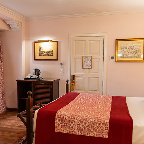 Chambre d'hôtel confortable avec lit king-size, coussins décoratifs et vue sur jardin intérieur. Profitez de votre séjour avec notre Juderia: Sevilla.