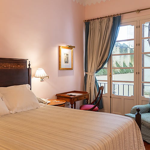 Détendez-vous dans cette chambre d'hôtel paisible avec un lit confortable, un fauteuil et une vue sur le balcon. Idéal pour votre séjour Juderia: Sevilla.