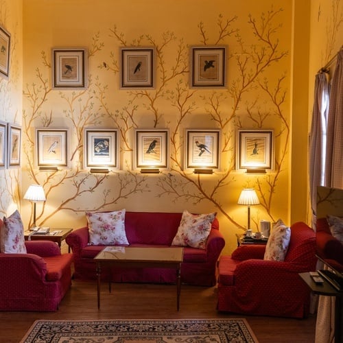 Elegant room in Juderia: Sevilla with red sofas, floral pillows, and bird artwork.