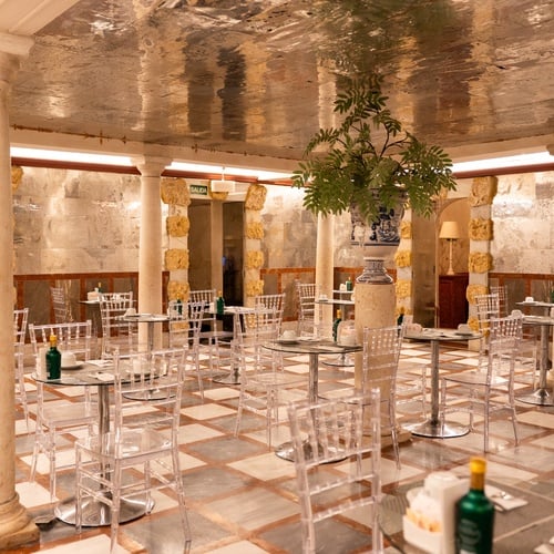 Elegant dining area at Juderia: Sevilla hotel with clear chairs and tables, and ornate pillars.