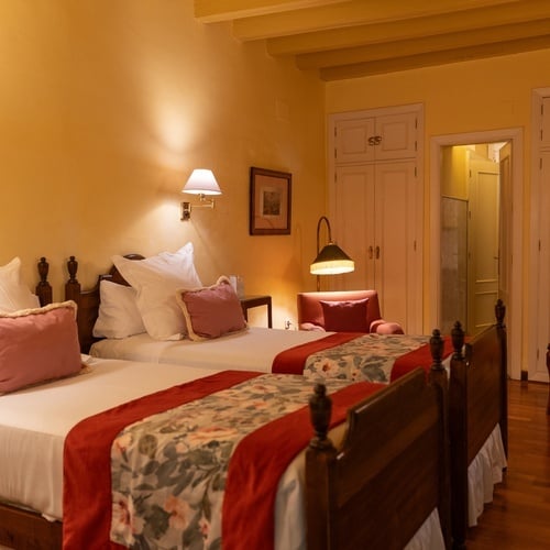 Cozy twin beds in a Juderia: Sevilla hotel room, with floral runners and soft lighting.