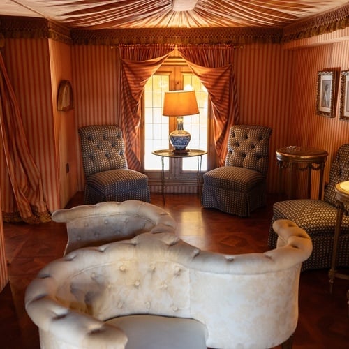 Elegant seating area in Judería, Sevilla, with ornate chairs, lamps, and striped walls.