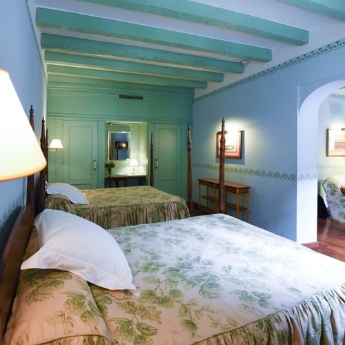 Classic Juderia: Sevilla hotel rooms with floral bedding and antique decor.