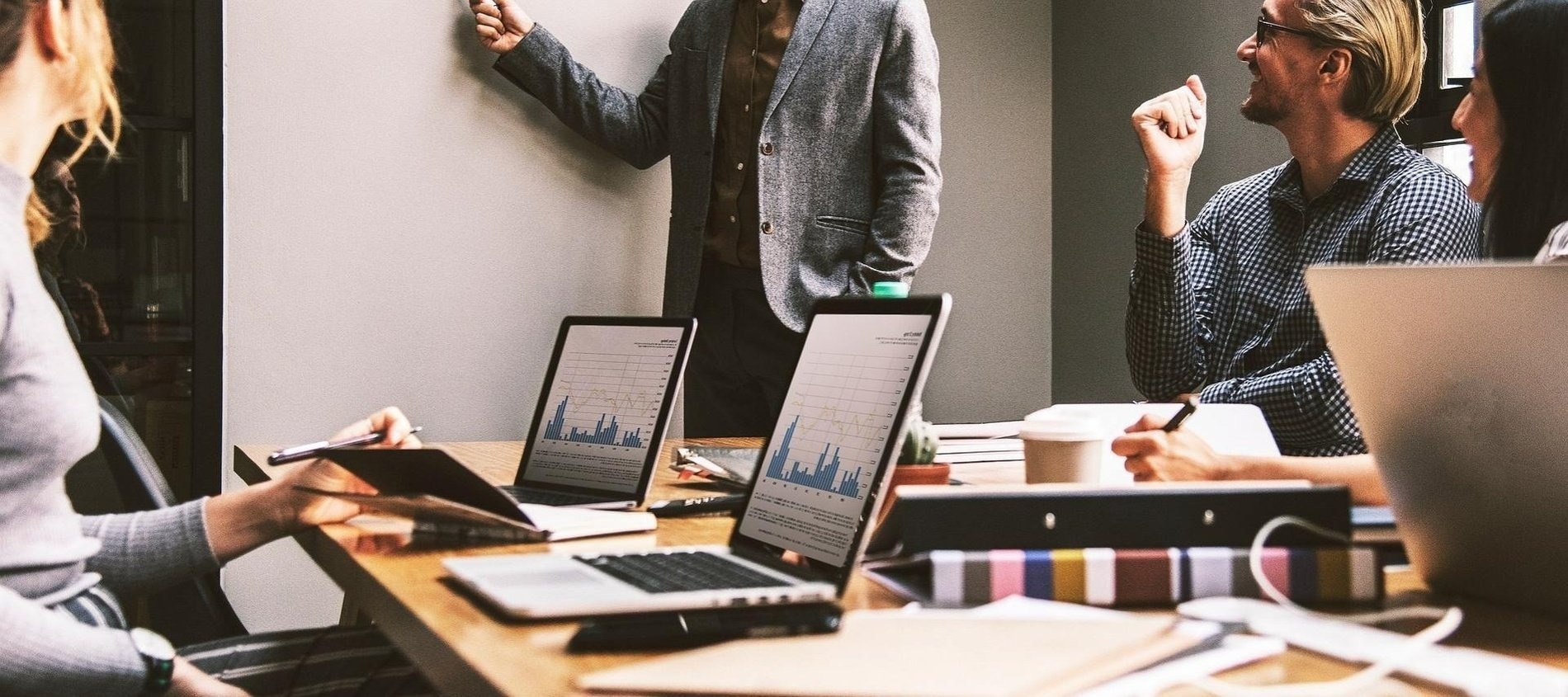 un grupo de personas están sentadas en una mesa con computadoras portátiles y una tableta