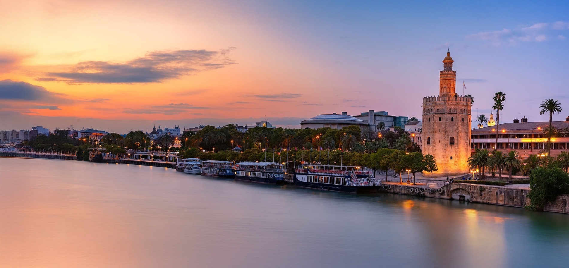 un río con barcos y una torre al atardecer