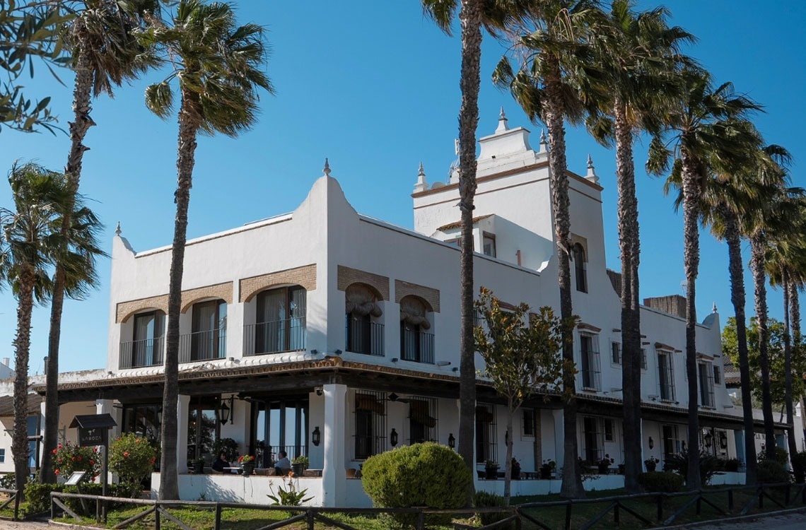 un edificio blanco rodeado de palmeras y un cielo azul
