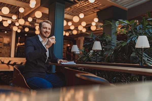 a man sitting at a table drinking a cup of coffee