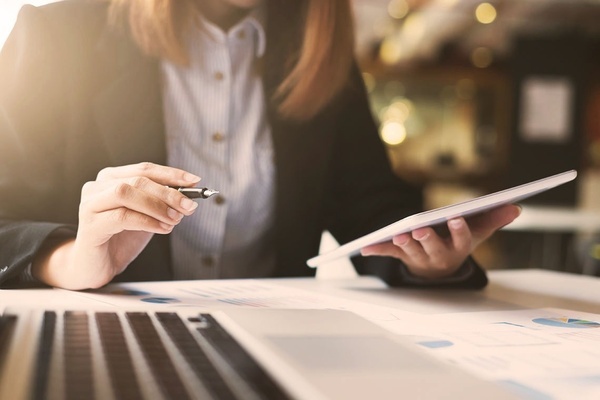 a woman is holding a pen and looking at a tablet