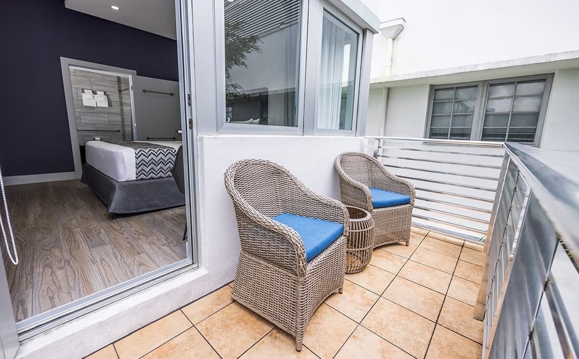 un balcón con dos sillas de mimbre y una mesa