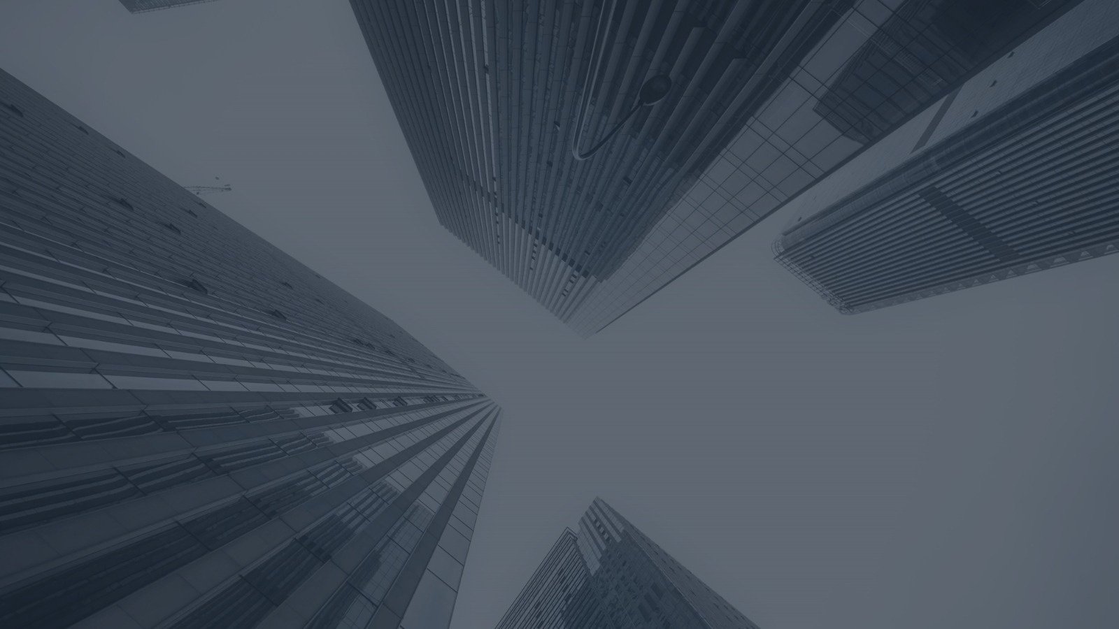 looking up at a row of tall buildings with a gray sky in the background