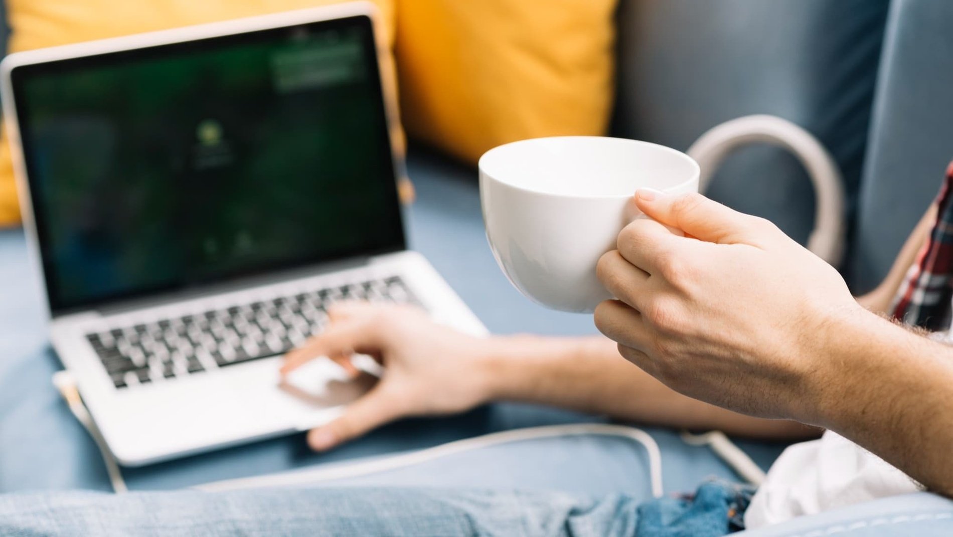 a person is holding a cup of coffee in front of a laptop