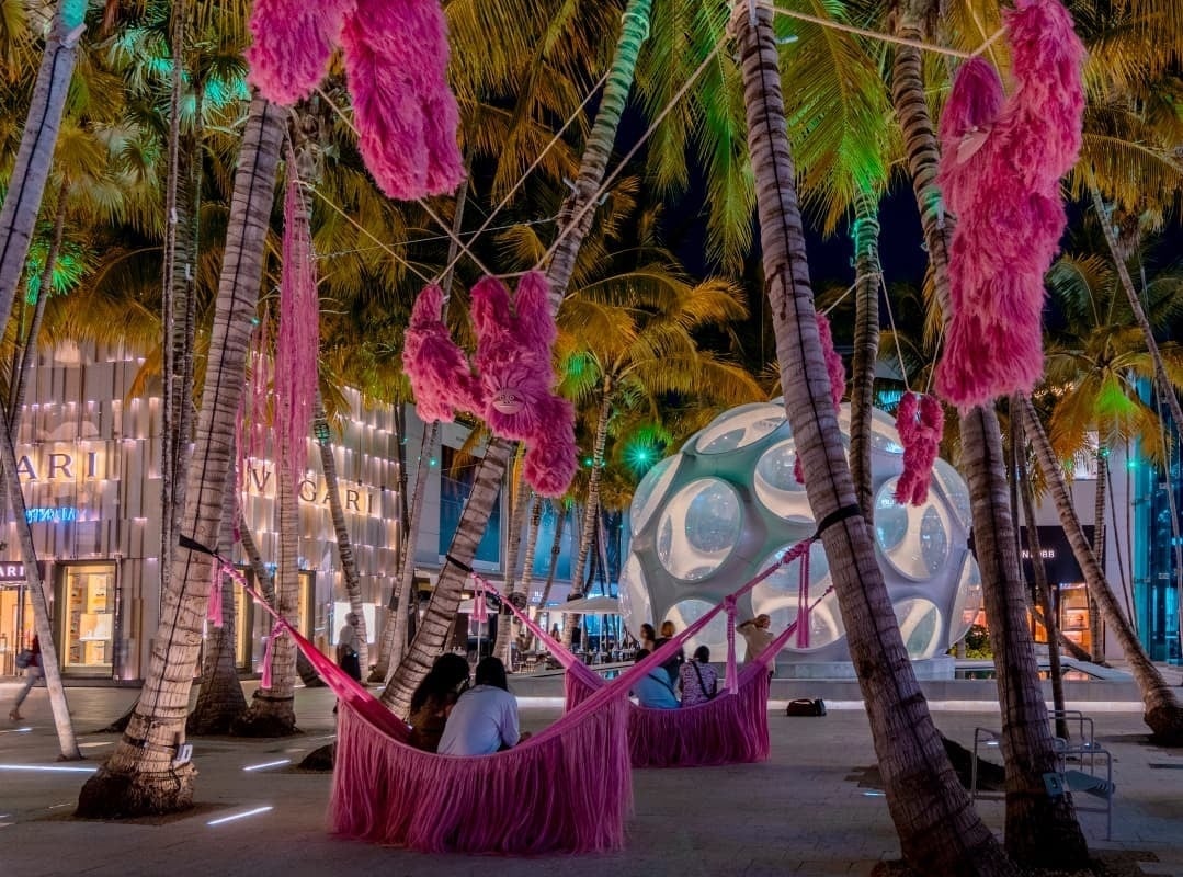 un grupo de personas se sienta en hamacas rosadas frente a una tienda bvlgari