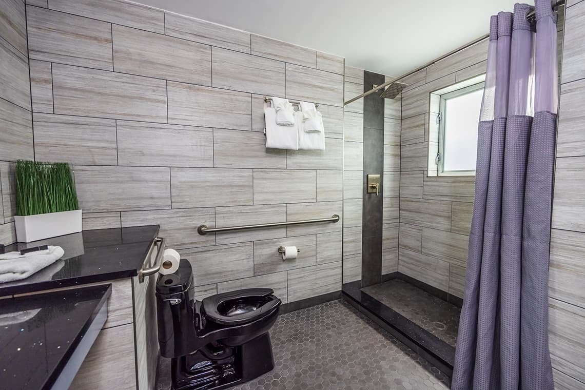 un baño con inodoro y ducha con cortina morada