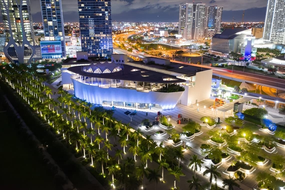 un camino de ladrillos conduce a un jardín con árboles y una estatua