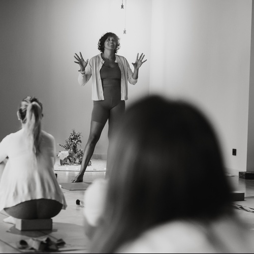 una dona parla a un grup de dones en un aula de yoga