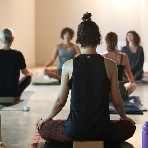 un grup de dones estant en lotus en una classe de yoga