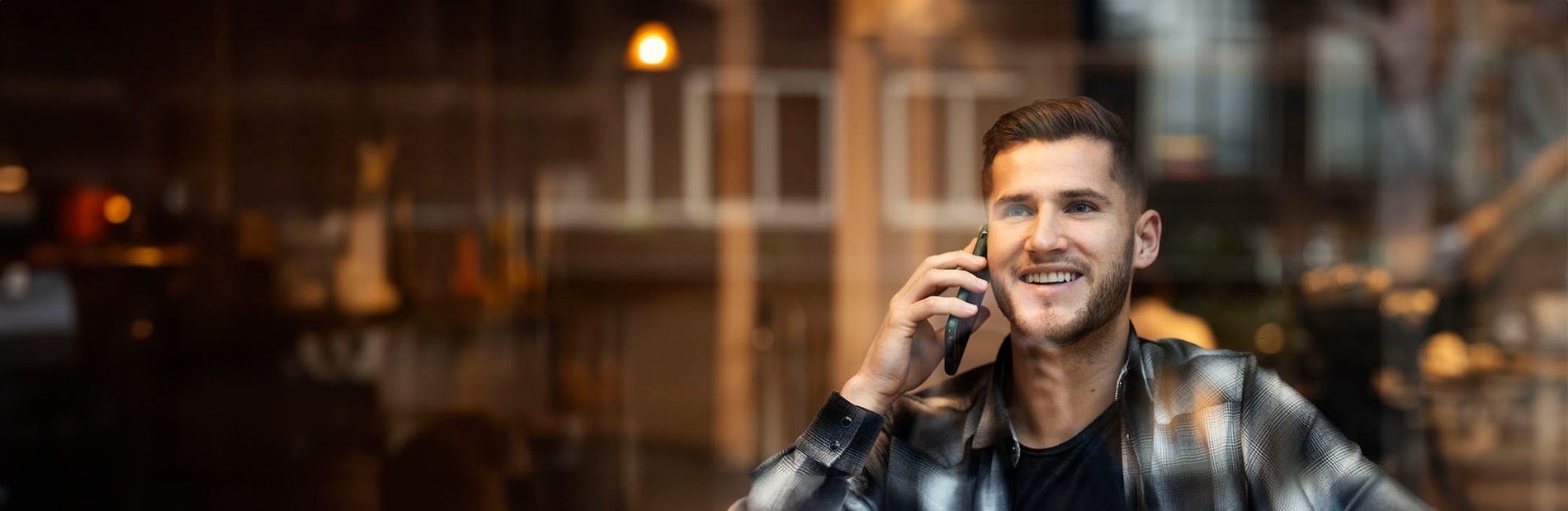 un hombre sonríe mientras habla por un teléfono celular