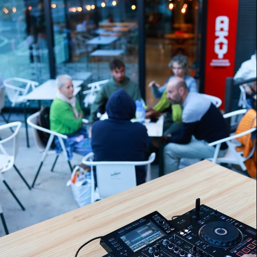 un dj toca la música en una taula de fusta davant d' un restaurant