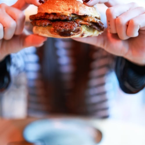 Chico joven mostrando una suculenta hamburguesa