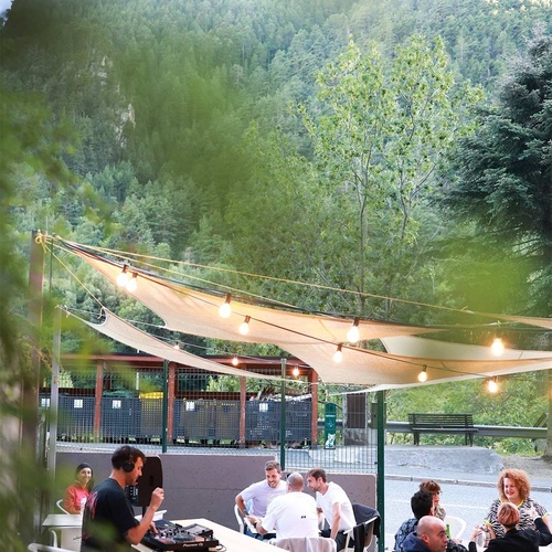 un grup de persones sent-se a l' aire lliure mentre un dj toca la música