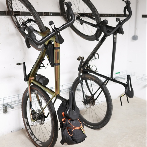 dues bicicletes estan penjades a una paret i una d' elles s'ha aixecat