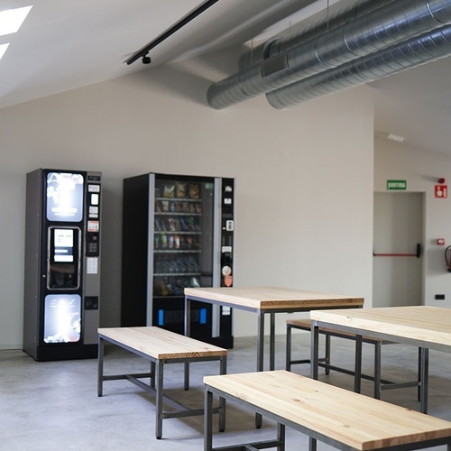 una sala de menjar amb bancs i una máquina de vending