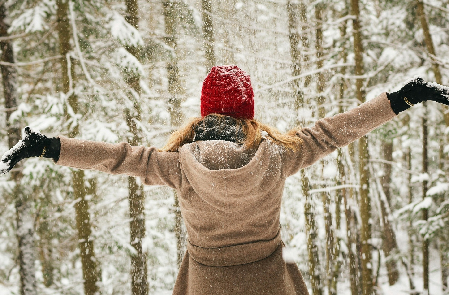 una mujer con un sombrero rojo lanza nieve en el aire