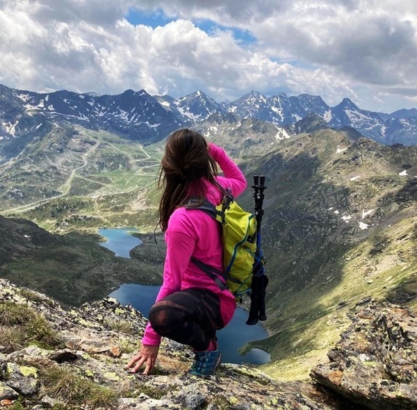 una mujer con una mochila verde se sienta en la cima de una montaña