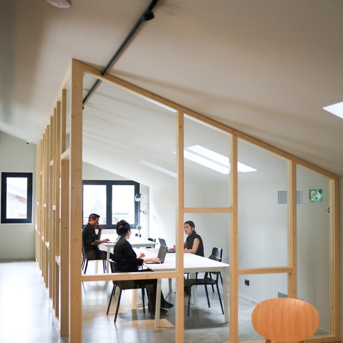 un grup de persones s'envolta en una sala de reunions amb una sortida de emergencia a la dreta