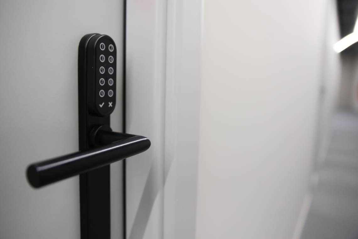 una puerta blanca con una manija negra y un teclado digital