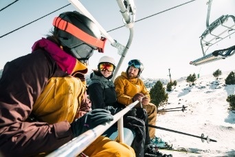 una piscina con sillas y sombrillas alrededor al atardecer