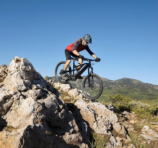 un hombre monta una bicicleta encima de una roca