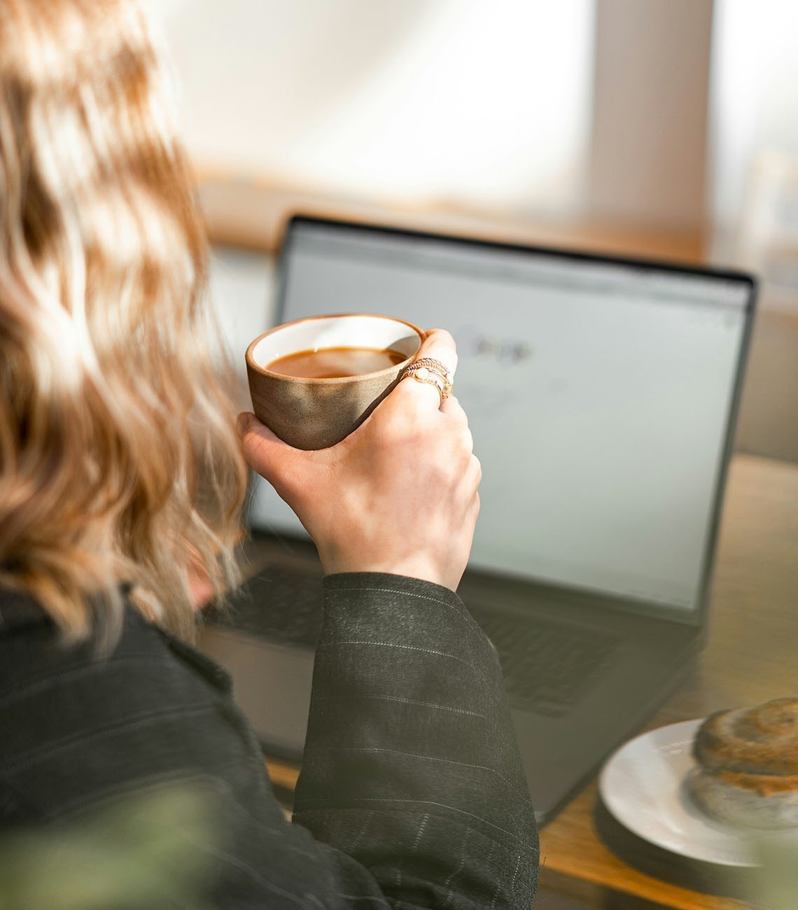 una mujer se sienta en un banco en un restaurante con una computadora portátil