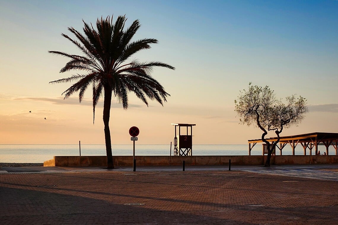 ein Strand mit weißem Sand und einem Boot im Hintergrund .