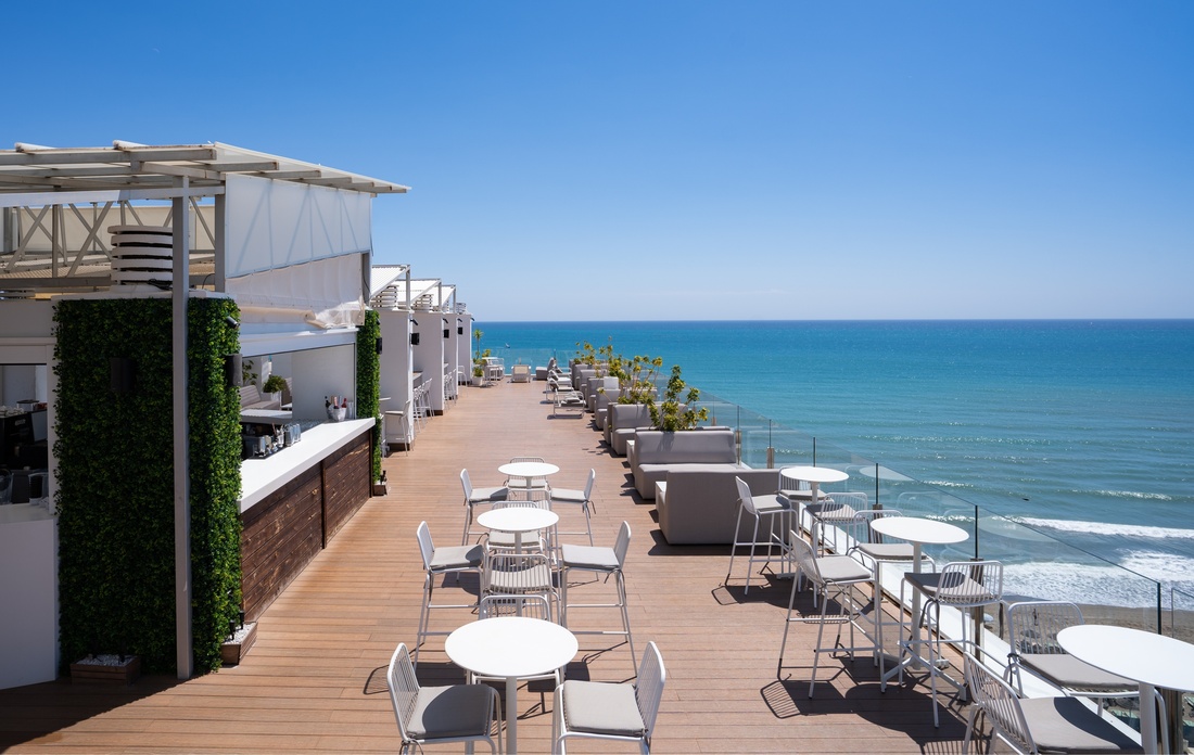 une terrasse avec des tables et des chaises au coucher du soleil