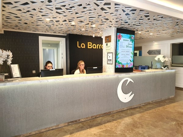 two women sitting at a desk in front of a sign that says la barra