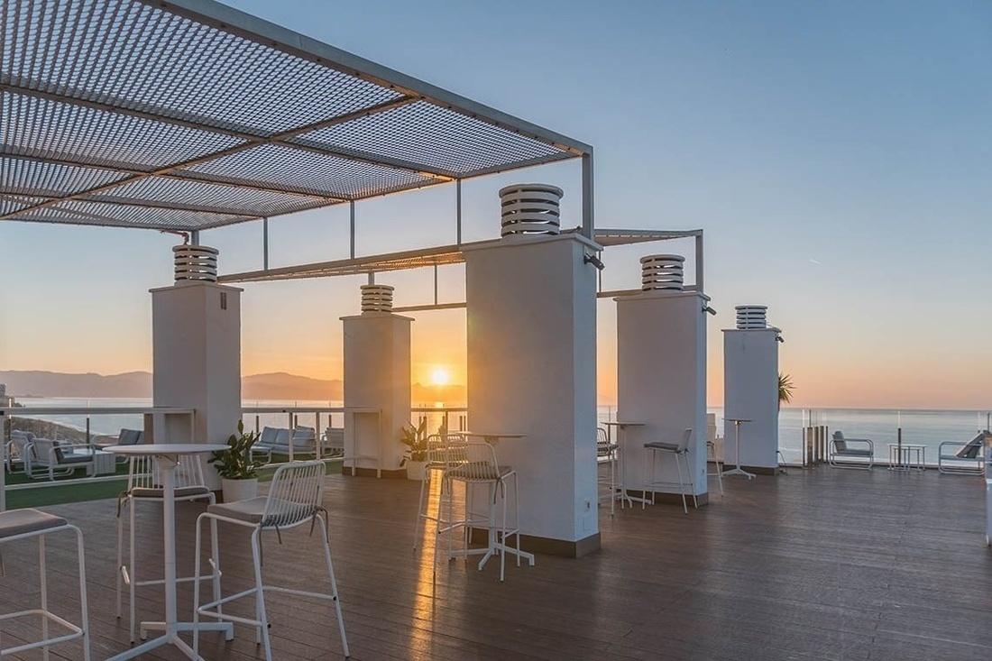 una terraza de madera con mesas y sillas al atardecer