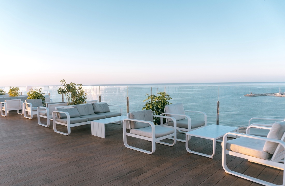 eine Reihe von weißen Möbeln auf einem Deck mit Blick auf das Meer