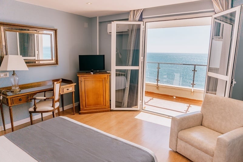 una habitación con una cama y una televisión con vista al océano