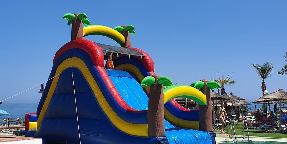 Aufblasbarer Wasserrutsche mit Palmen an einem Strand