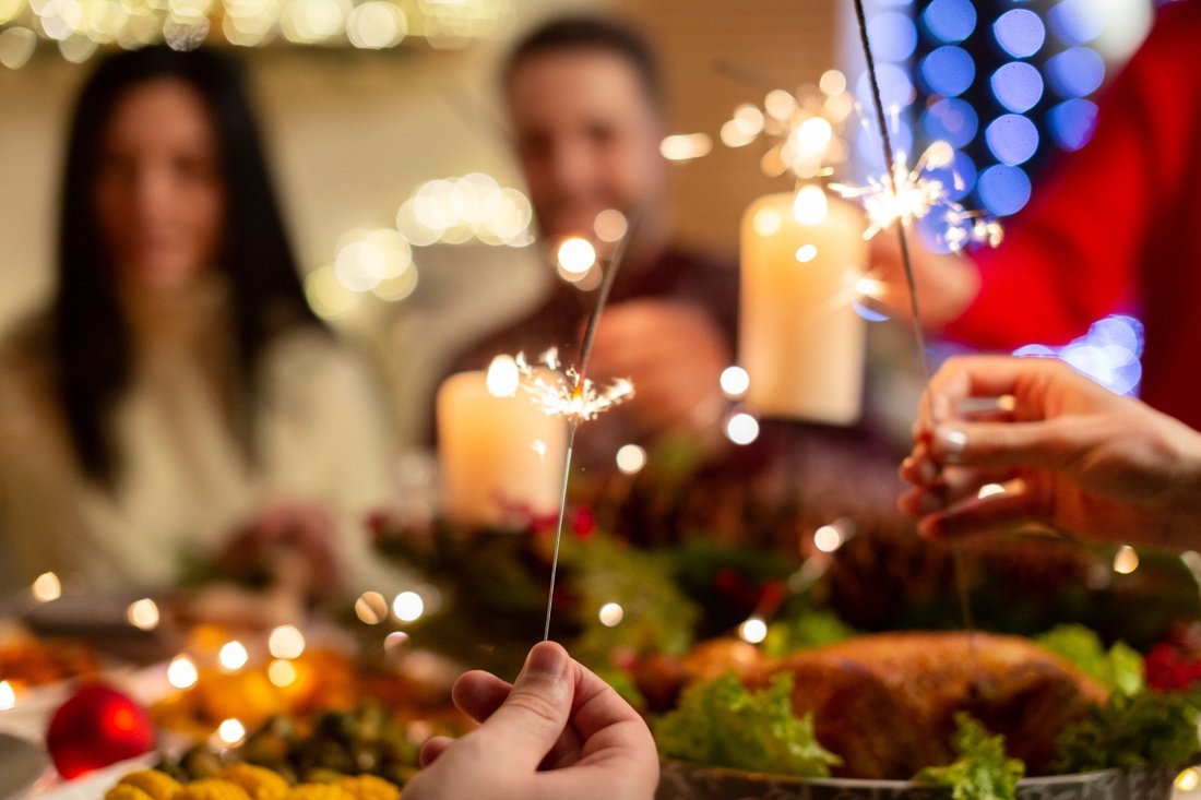 un grupo de personas sostiene sparklers frente a una mesa de navidad